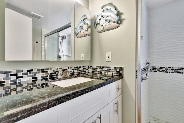 bathroom featuring backsplash, vanity, and a shower with shower door