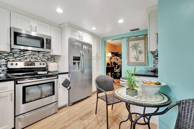 kitchen with backsplash, light hardwood / wood-style flooring, appliances with stainless steel finishes, and white cabinetry