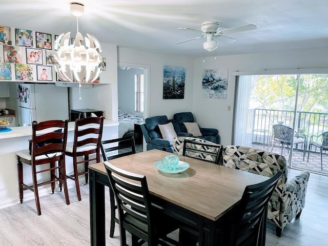 dining area with ceiling fan with notable chandelier and light hardwood / wood-style flooring