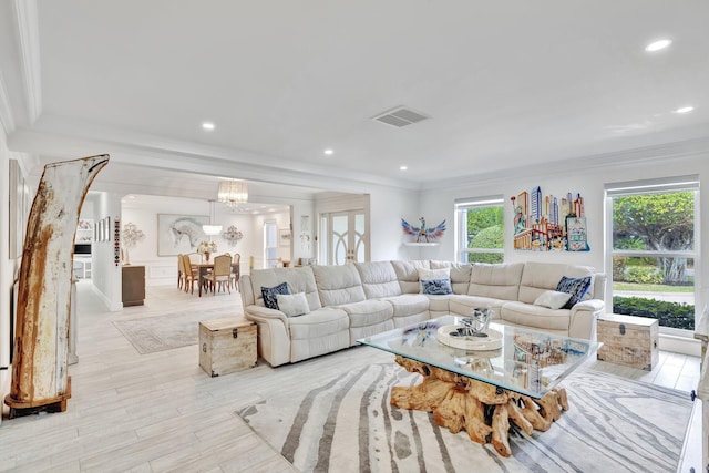 living room with ornamental molding, light wood-type flooring, a healthy amount of sunlight, and a notable chandelier