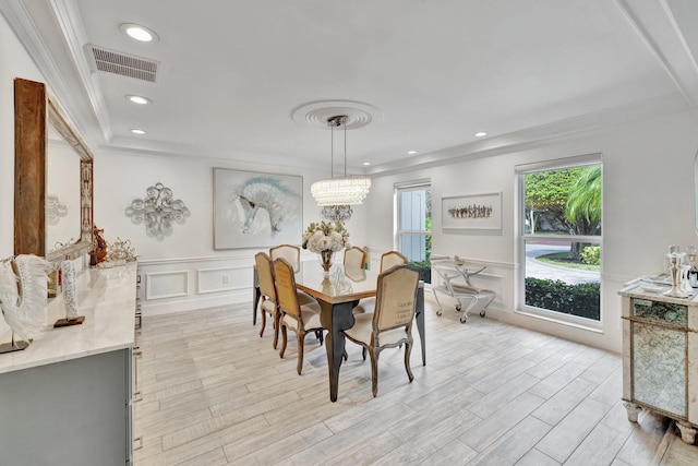 dining room with a chandelier, light wood-type flooring, and crown molding