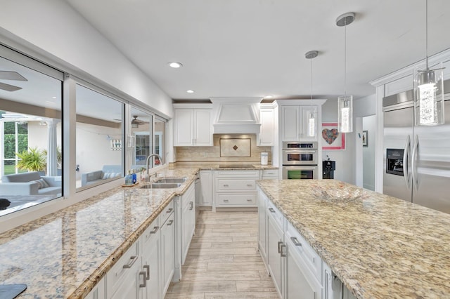 kitchen featuring tasteful backsplash, sink, white cabinets, and hanging light fixtures