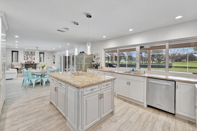 kitchen with dishwasher, ceiling fan, decorative light fixtures, a kitchen island, and white cabinetry