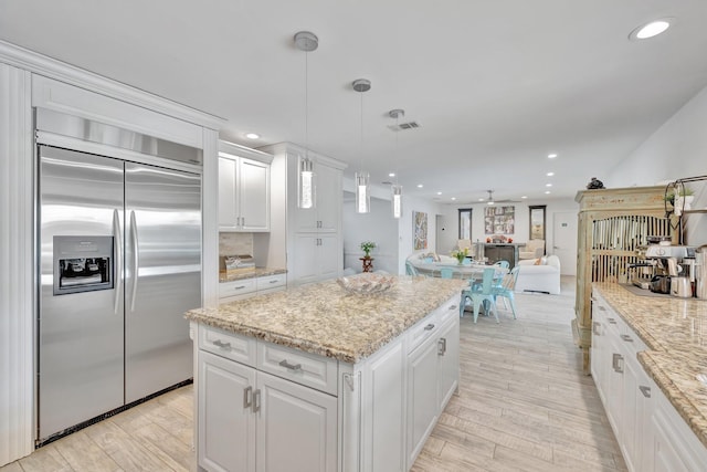 kitchen with white cabinets, ceiling fan, built in fridge, and hanging light fixtures