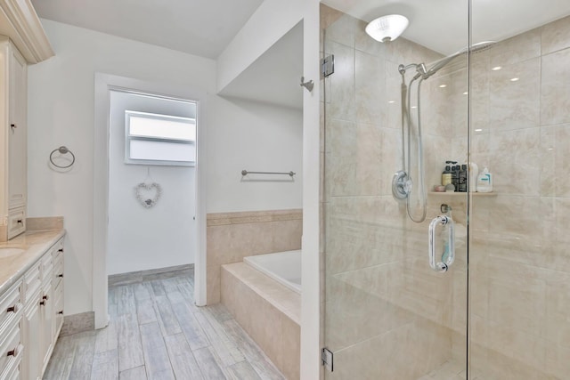 bathroom featuring hardwood / wood-style flooring, vanity, and plus walk in shower