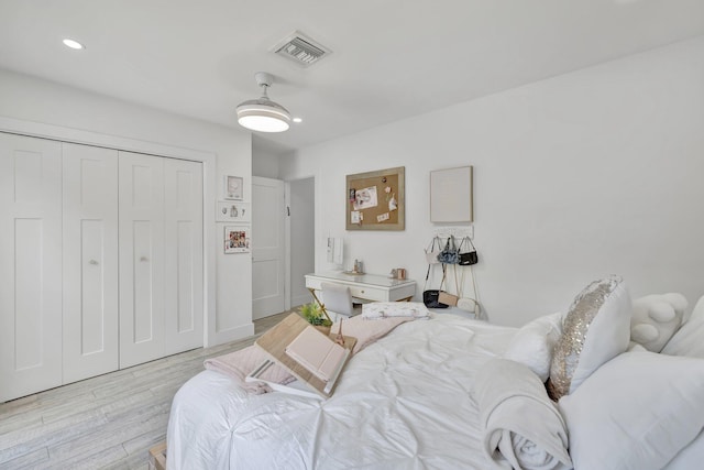 bedroom with ceiling fan, light wood-type flooring, and a closet