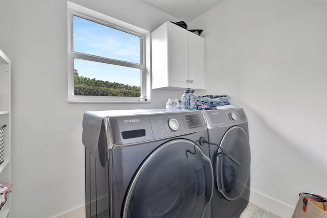 clothes washing area with washer and clothes dryer and cabinets