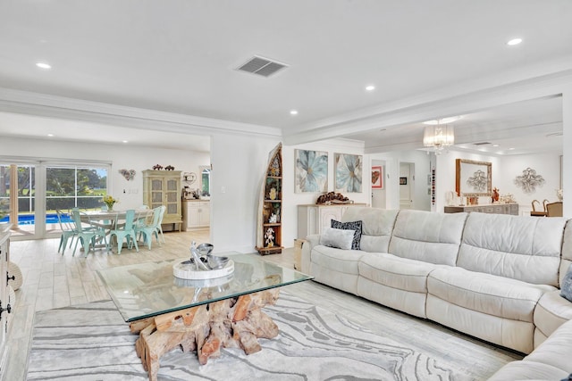 living room featuring crown molding, light hardwood / wood-style floors, and a notable chandelier