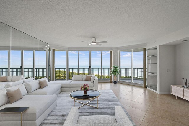 living room with a textured ceiling, light tile patterned floors, a wall of windows, and a water view