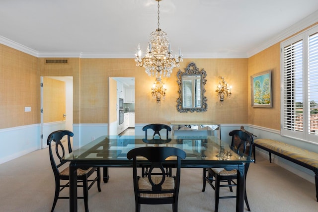 carpeted dining room with a wainscoted wall, visible vents, a notable chandelier, crown molding, and wallpapered walls