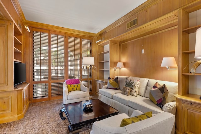 carpeted living room with wooden walls, ornamental molding, and built in features