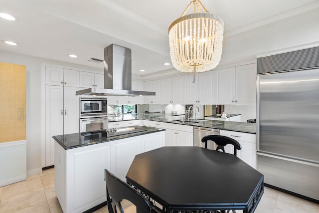 kitchen with island range hood, built in appliances, a kitchen island, white cabinetry, and an inviting chandelier