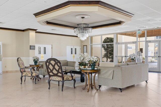 living room featuring crown molding, a raised ceiling, french doors, expansive windows, and a notable chandelier