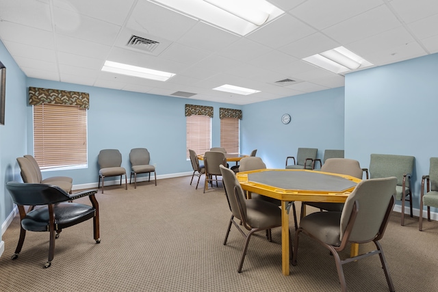 carpeted dining area with a drop ceiling