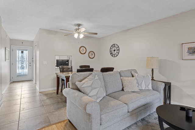 living room featuring ceiling fan, light hardwood / wood-style flooring, and a textured ceiling