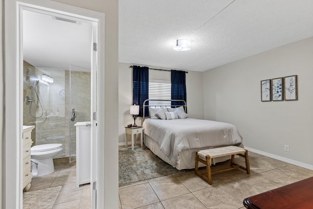 bedroom with ensuite bathroom, light tile patterned floors, and a textured ceiling