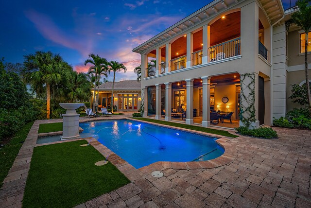 pool at dusk featuring a patio area and pool water feature