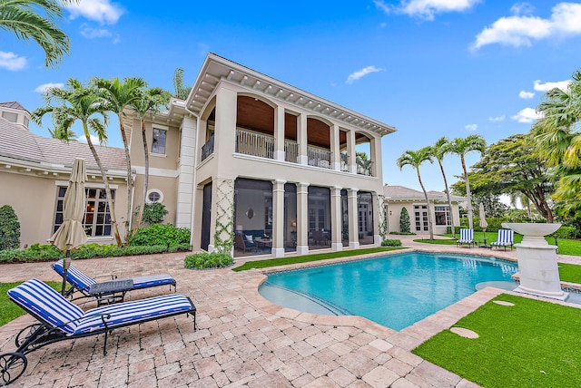 rear view of property with a balcony, a patio, and french doors