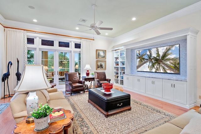 living room with ornamental molding, ceiling fan, built in shelves, and light hardwood / wood-style flooring