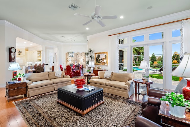 living room with hardwood / wood-style floors, ornamental molding, and ceiling fan