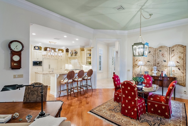 dining room featuring a notable chandelier, light wood-type flooring, and crown molding