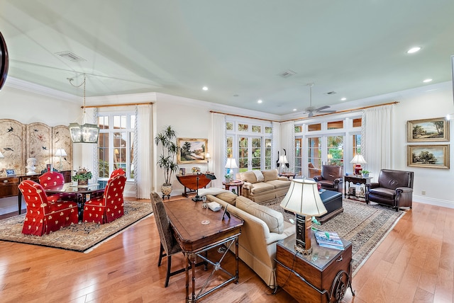 living room with crown molding, light hardwood / wood-style floors, french doors, and ceiling fan with notable chandelier