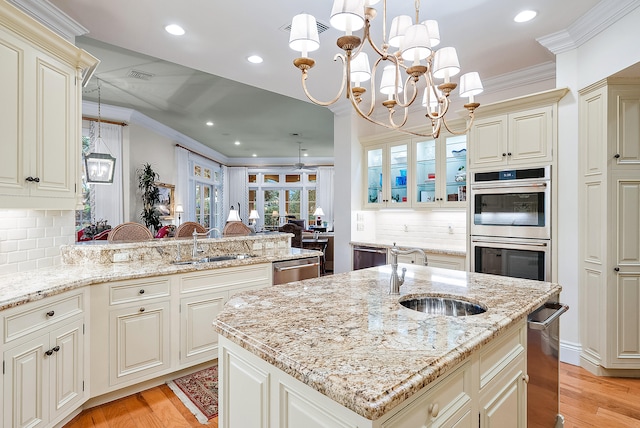 kitchen with backsplash, hanging light fixtures, an island with sink, and crown molding