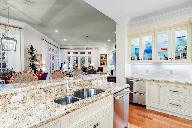 kitchen with pendant lighting, light hardwood / wood-style floors, ceiling fan, tasteful backsplash, and light stone counters