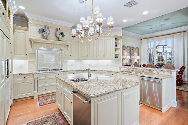 kitchen with decorative light fixtures, stainless steel appliances, light wood-type flooring, and an island with sink