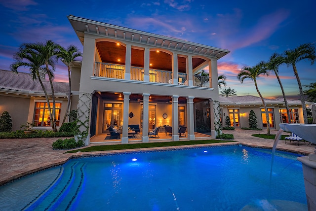 pool at dusk featuring french doors and a patio