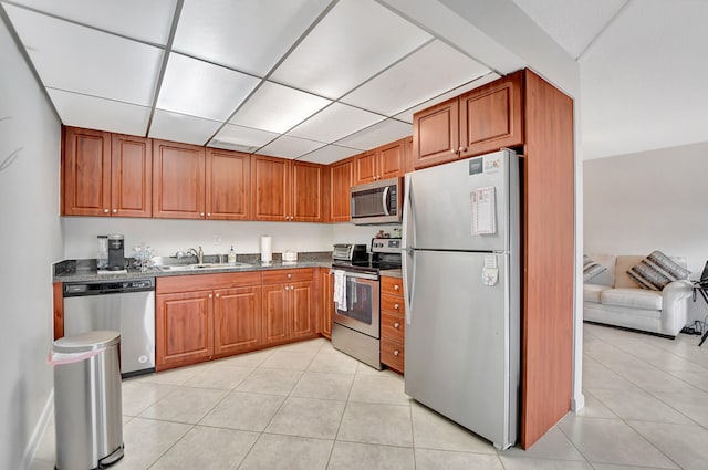 kitchen with dark stone counters, sink, light tile flooring, and stainless steel appliances