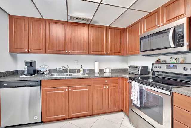 kitchen featuring dark stone countertops, light tile flooring, sink, and stainless steel appliances