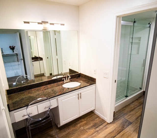 bathroom with wood-type flooring, a shower with shower door, and vanity