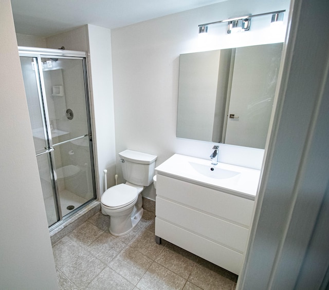 bathroom with a shower with door, tile flooring, vanity with extensive cabinet space, and toilet