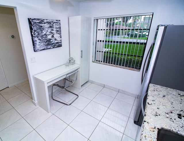 interior space with stainless steel fridge and light tile floors