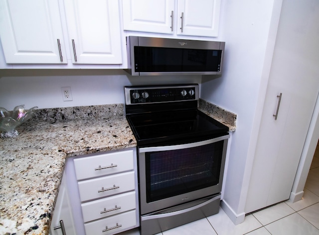 kitchen with light tile floors, white cabinets, light stone counters, and stainless steel appliances