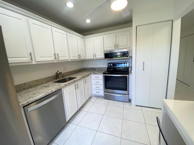 kitchen with sink, light tile floors, stainless steel appliances, light stone countertops, and white cabinetry