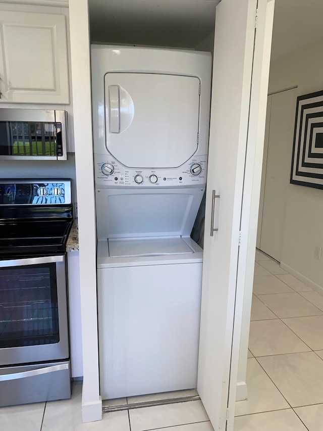 laundry area featuring light tile floors and stacked washing maching and dryer