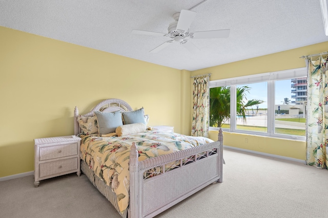 bedroom with a textured ceiling, light colored carpet, and ceiling fan