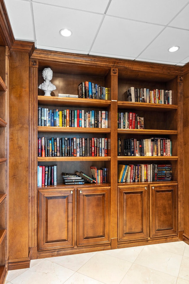 interior space with a paneled ceiling and light tile flooring