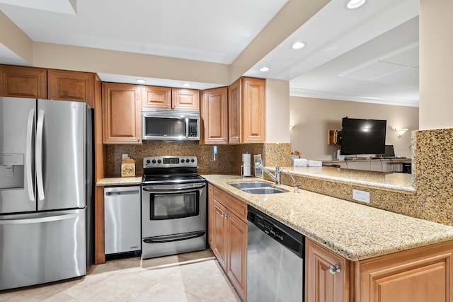 kitchen with kitchen peninsula, light stone countertops, sink, stainless steel appliances, and tasteful backsplash