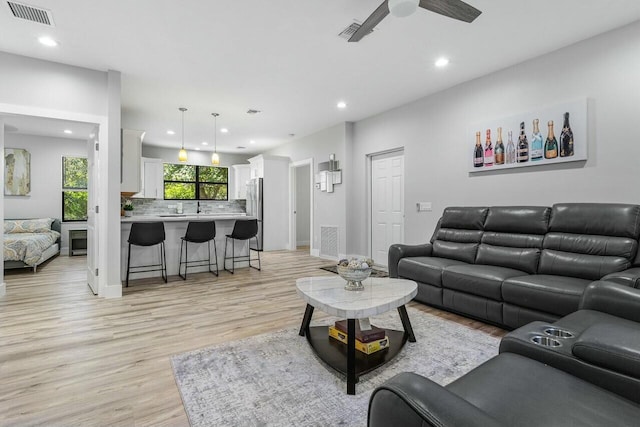 living room with ceiling fan and light hardwood / wood-style flooring