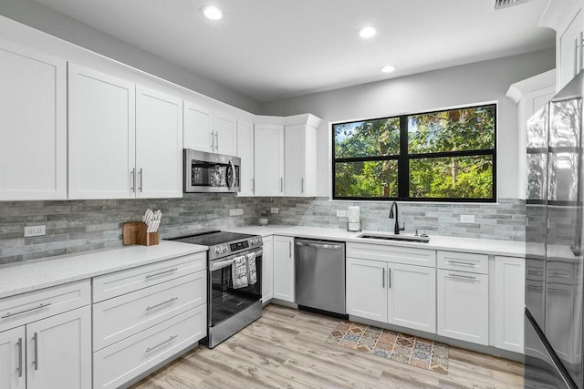 kitchen featuring white cabinets, sink, appliances with stainless steel finishes, and light hardwood / wood-style flooring