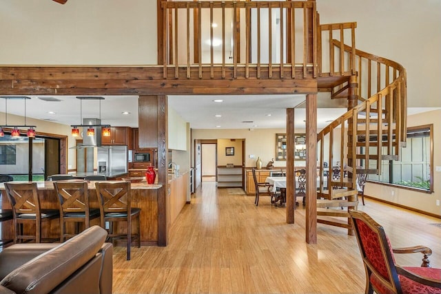 kitchen with pendant lighting, stone counters, ceiling fan with notable chandelier, light hardwood / wood-style flooring, and kitchen peninsula