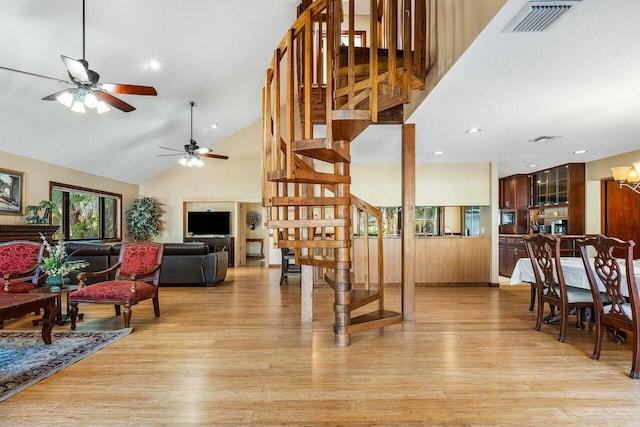 living room with ceiling fan, light hardwood / wood-style floors, a textured ceiling, and vaulted ceiling