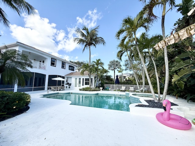 view of pool featuring a patio, fence, and a pool with connected hot tub