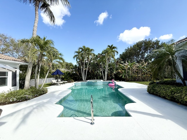 view of pool featuring fence, a pool with connected hot tub, and a patio area