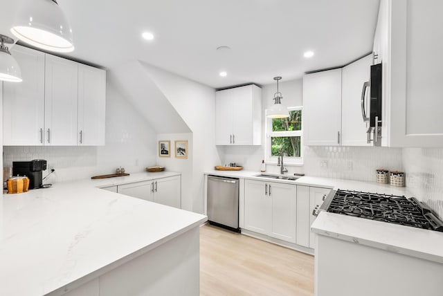 kitchen with pendant lighting, sink, white cabinetry, stainless steel appliances, and light stone countertops