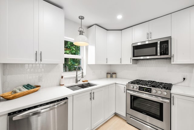 kitchen featuring white cabinetry, stainless steel appliances, sink, and hanging light fixtures