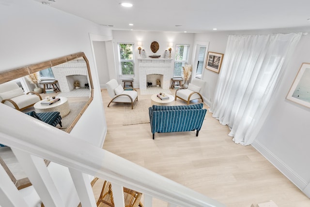 living room featuring a brick fireplace and light hardwood / wood-style floors